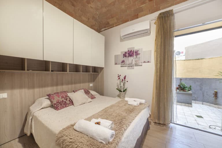 Camera da letto con letto matrimoniale, arredamento moderno, soffitto in mattoni a vista e accesso a un piccolo patio esterno