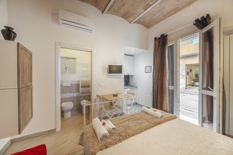 Monolocale con soffitto in mattoni a volta, letto matrimoniale in ferro battuto, angolo cottura attrezzato, tavolo da pranzo e bagno moderno. Porta-finestra con accesso diretto alla strada.