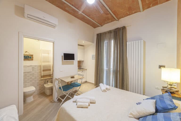 Camera accogliente con letto matrimoniale, cucina attrezzata e bagno privato, arredata in stile moderno con dettagli rustici.