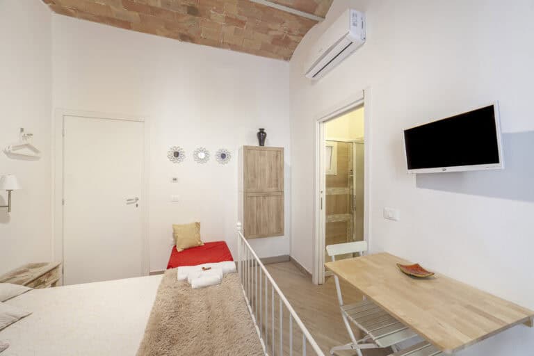 Camera con letto matrimoniale e letto singolo, bagno privato e arredamento moderno con dettagli rustici.