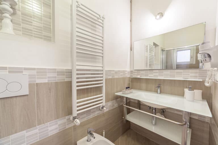 Bagno moderno con lavabo in vetro, bidet, scalda salviette e ampia specchiera.